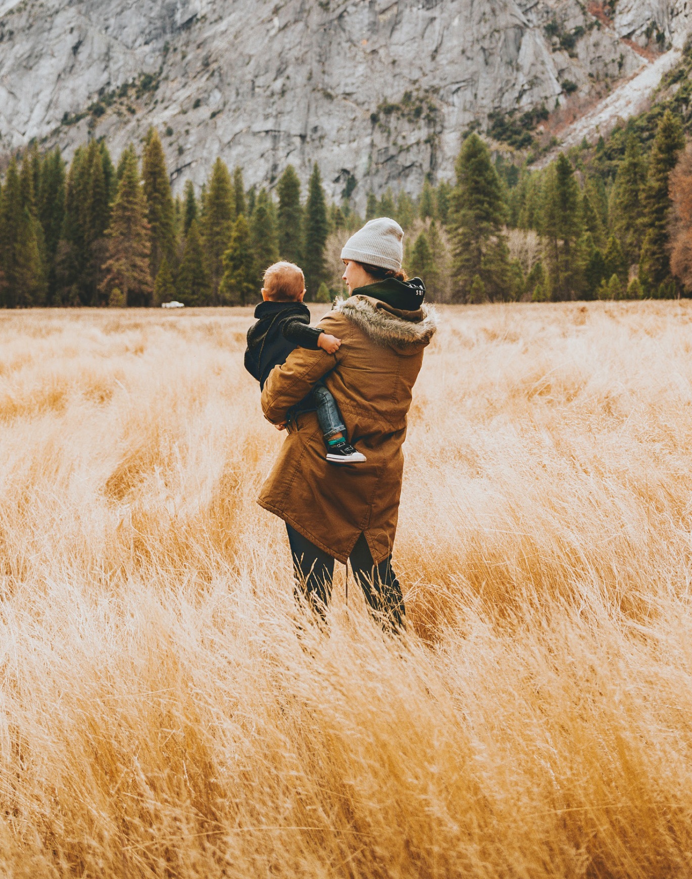 woman holding baby near mountain